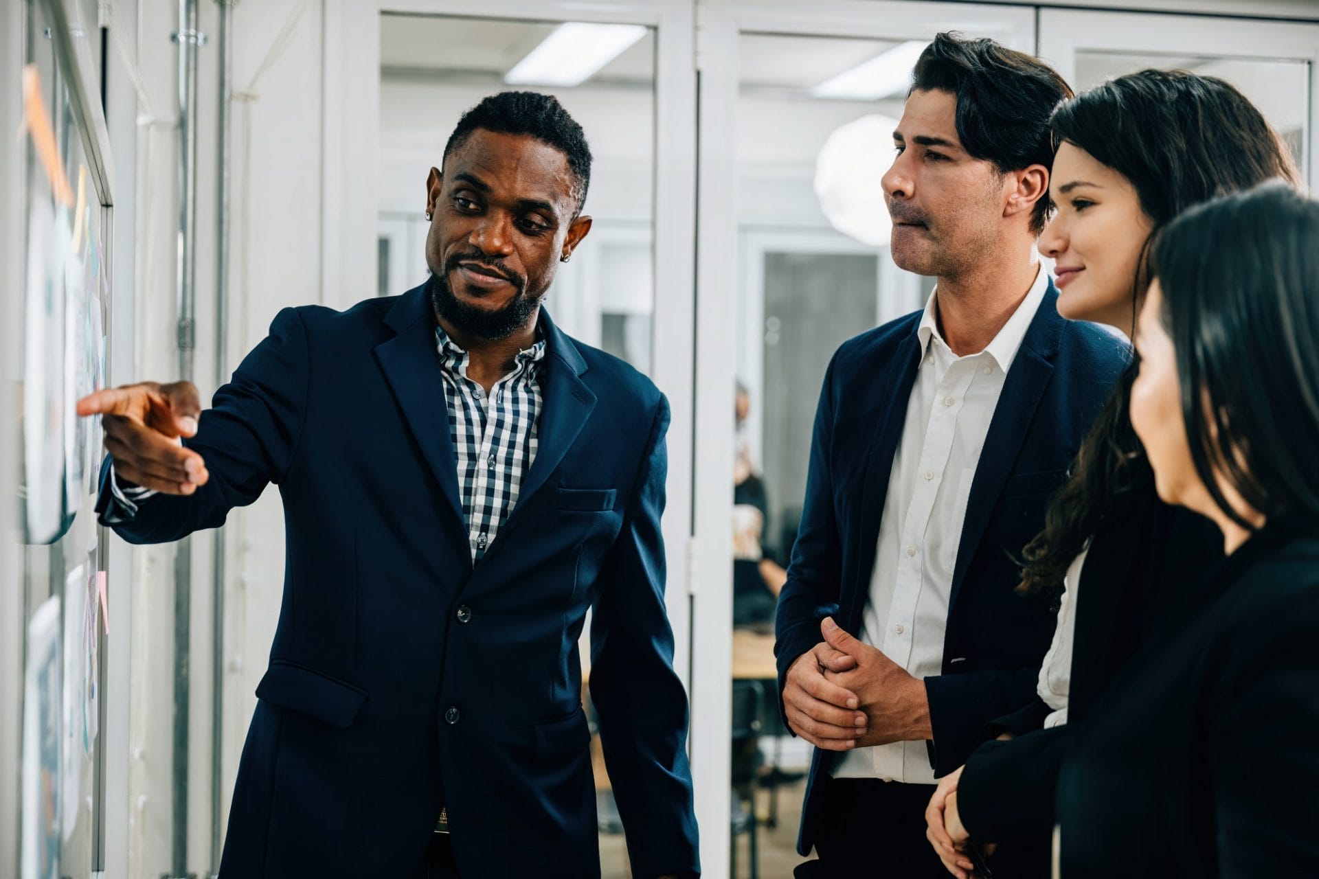 In a dynamic business office setting, colleagues gather around a board. The black businessman leads