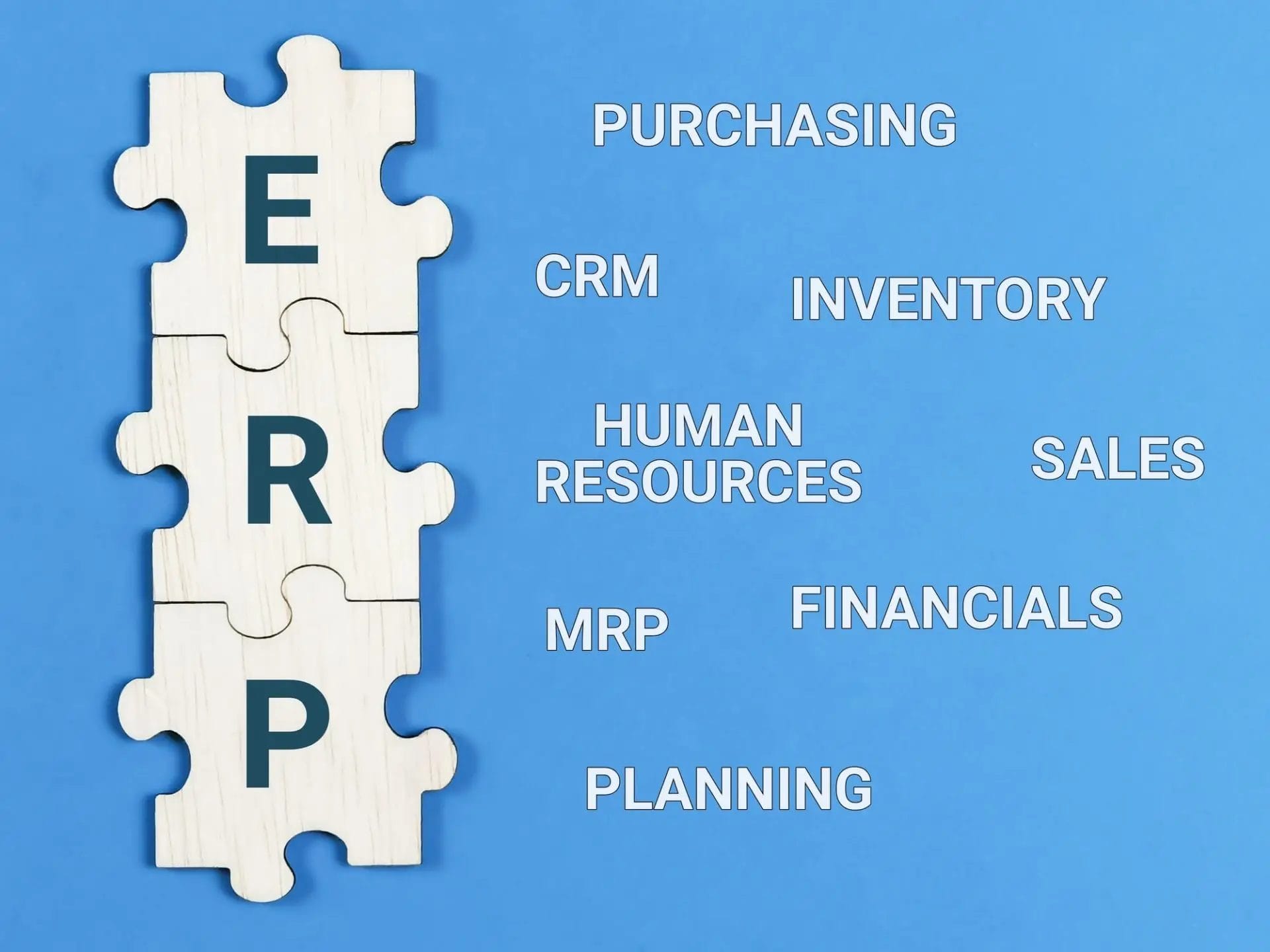 Enterprise Resource Planning concept. Text ERP with jigsaw puzzle pieces on blue background.