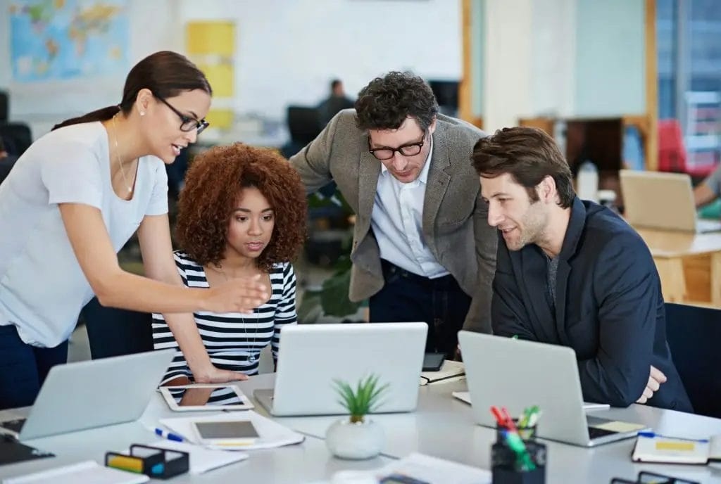 Streamlining their online site. Cropped shot of business people working on laptops around a table.