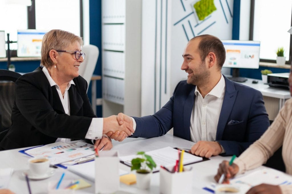 Consultant greeting international client with handshake after partnership