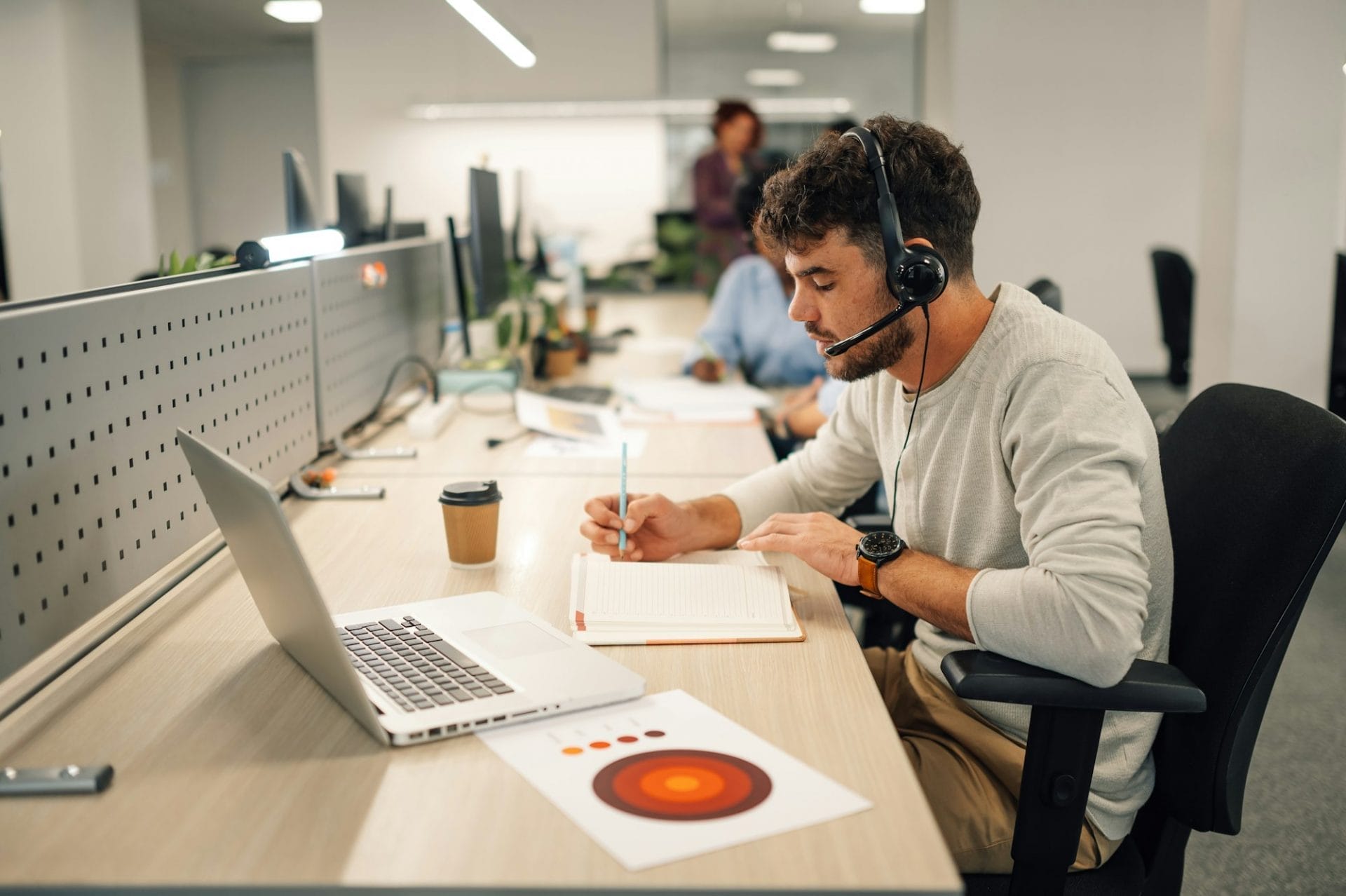 Customer services agent with headset writing notes in a call center
