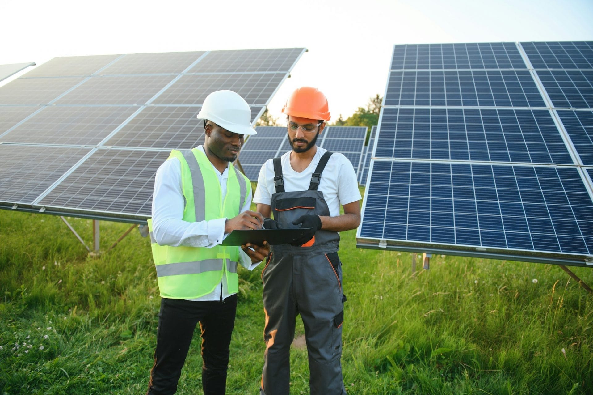A team of multiracial workers in a field of solar panels.
